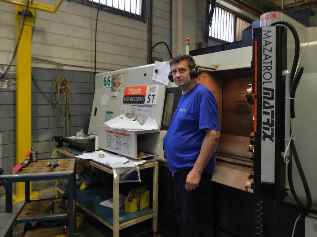 Operator in hearing protection beside a Mazak Integrex machine
