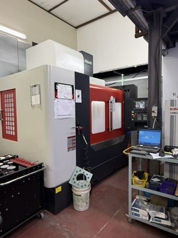 Vertical CNC machining centre with a laptop on a tool cart